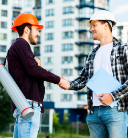 Two men shaking hands after a construction deal with a building in the background