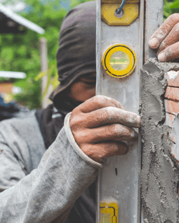 Worker checking the level of concrete using a level bar against the wall.