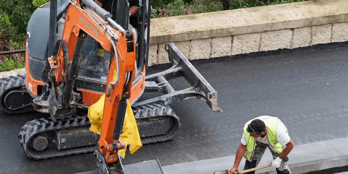 Machine truck repairing a sidewalk with construction equipment.