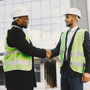 Contractors shaking hands with a building in the background