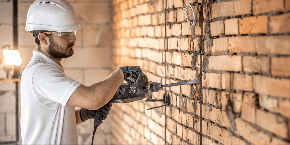 Mason performing repointing work on an old brick wall.