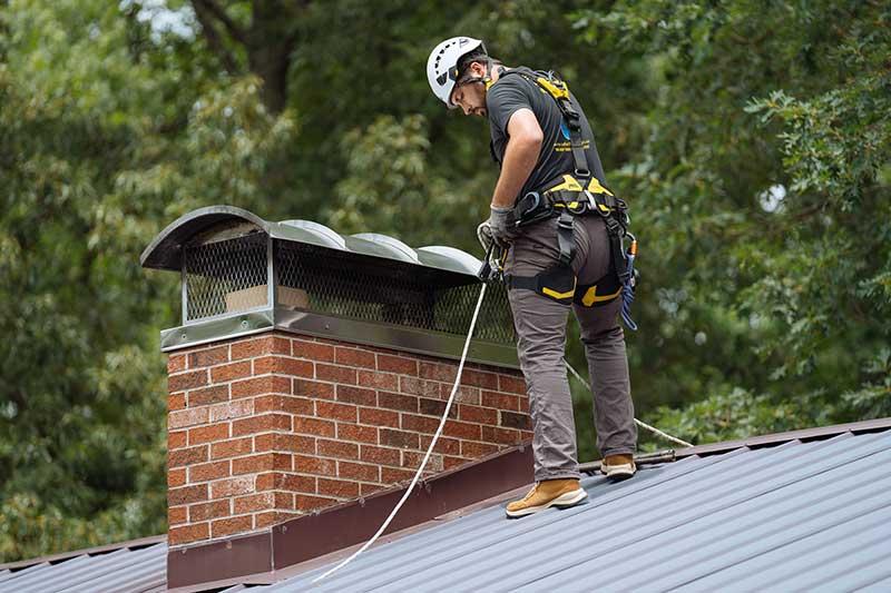 chimney repair near me NYC worker repairing damaged brick chimney on rooftop