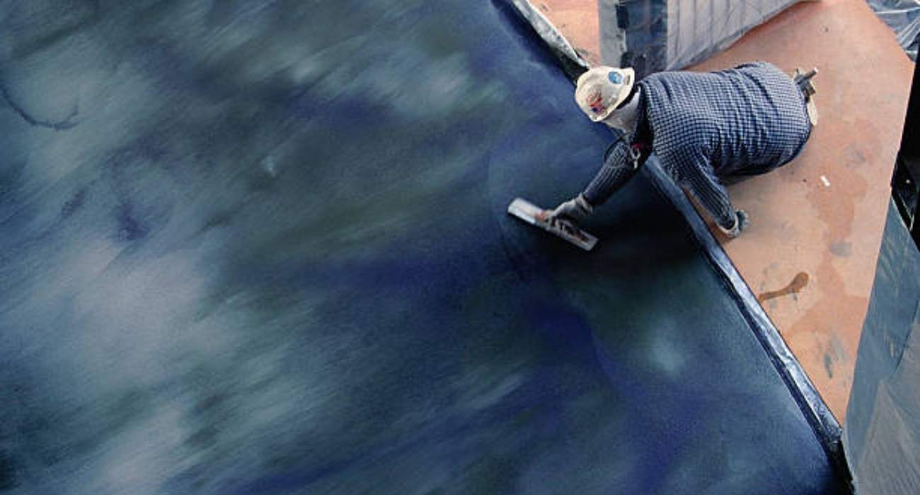 Worker applying Thoroseal waterproofing coating on concrete surface with trowel for smooth, protective finish