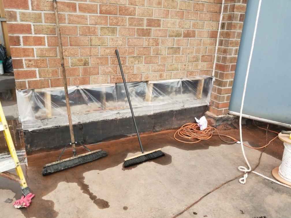 Foundation wall crack repair and waterproofing preparation work on a brick building by NuEra Contracting